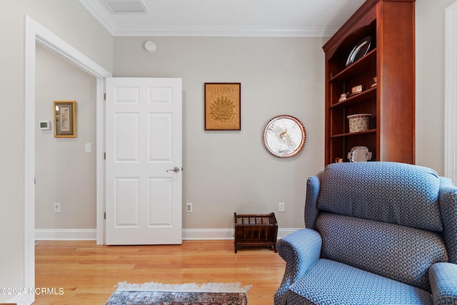 sitting room with crown molding and light hardwood / wood-style flooring