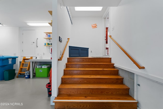 stairs featuring finished concrete flooring and a skylight