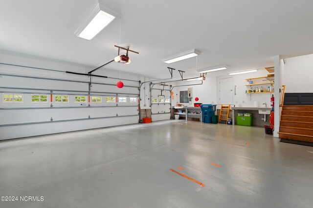 garage featuring a garage door opener, electric panel, and a workshop area