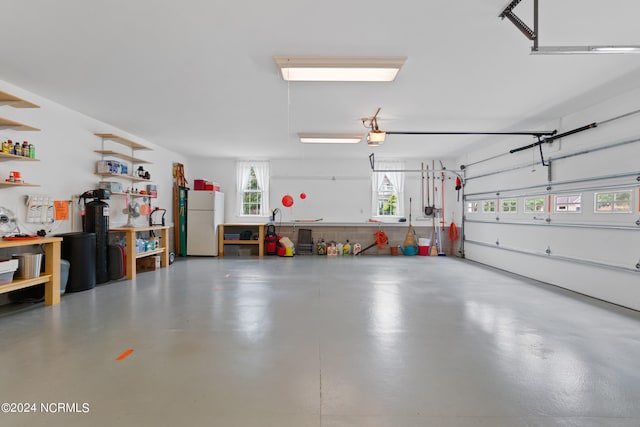 garage featuring a garage door opener, freestanding refrigerator, and a workshop area