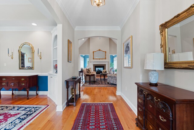 entrance foyer featuring vaulted ceiling, ornamental molding, and light hardwood / wood-style flooring