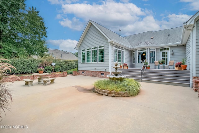 rear view of house with crawl space, roof with shingles, and a patio