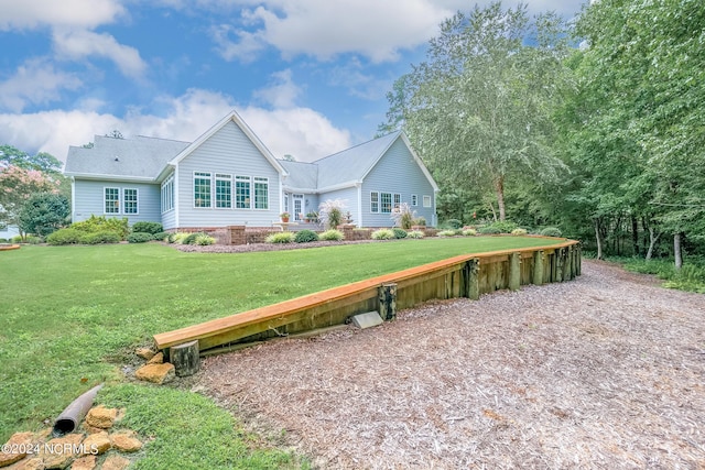 rear view of property featuring driveway and a lawn