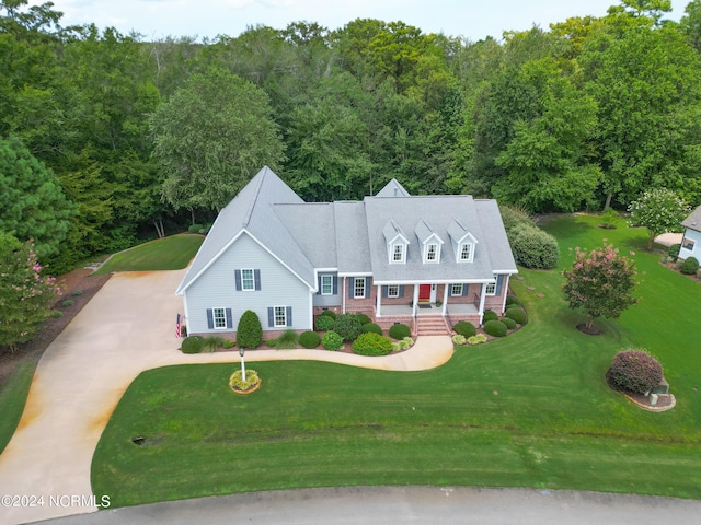 cape cod house featuring driveway, a front yard, and covered porch