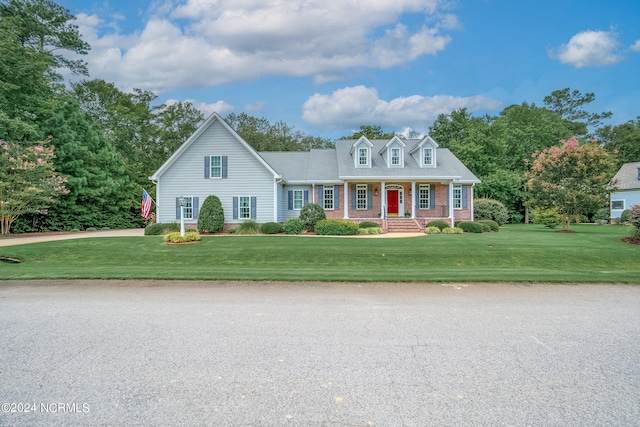 cape cod-style house featuring covered porch and a front lawn