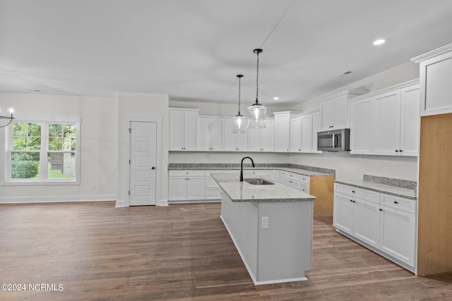 kitchen featuring white cabinets, sink, wood-type flooring, and a center island with sink