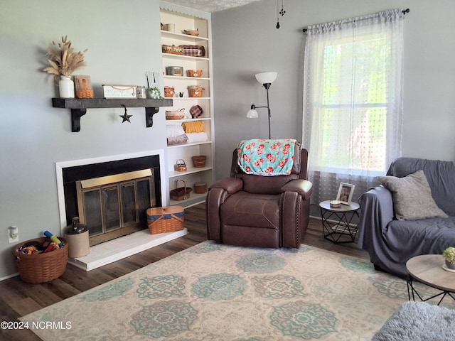 sitting room with plenty of natural light, wood finished floors, and a glass covered fireplace