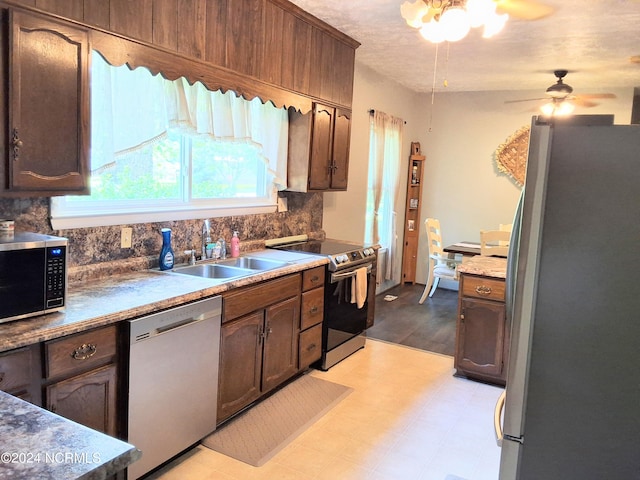 kitchen featuring a sink, a ceiling fan, appliances with stainless steel finishes, backsplash, and light floors