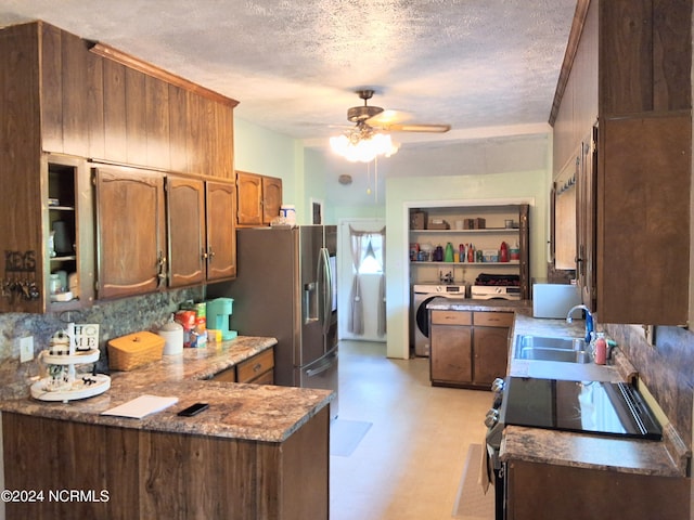 kitchen featuring a textured ceiling, a peninsula, a sink, a ceiling fan, and light floors