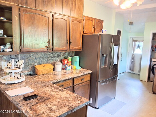 kitchen featuring light stone counters, brown cabinets, stainless steel refrigerator with ice dispenser, light floors, and tasteful backsplash