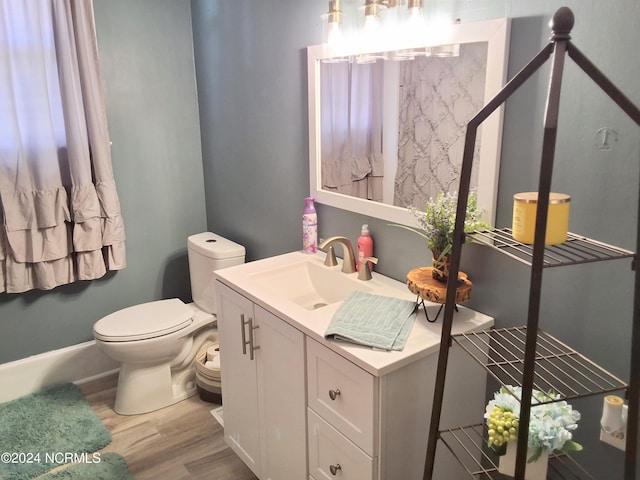 bathroom with toilet, wood finished floors, and vanity