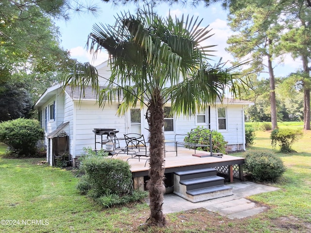 back of house featuring a lawn and a wooden deck