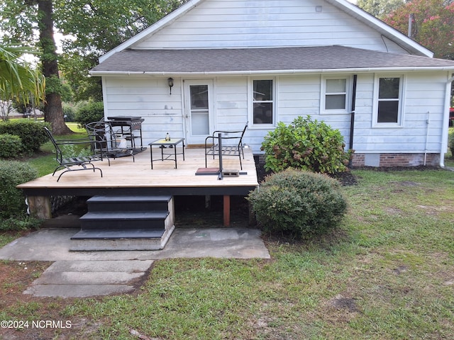 rear view of property featuring crawl space, a shingled roof, a deck, and a yard