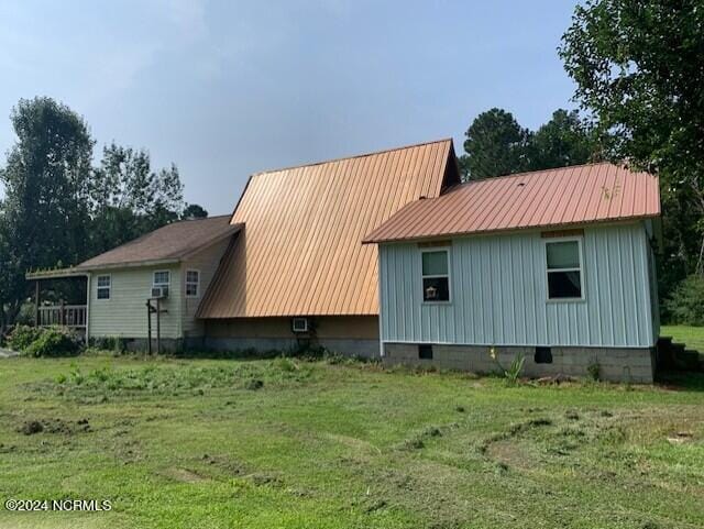 view of side of property featuring metal roof, a yard, and crawl space