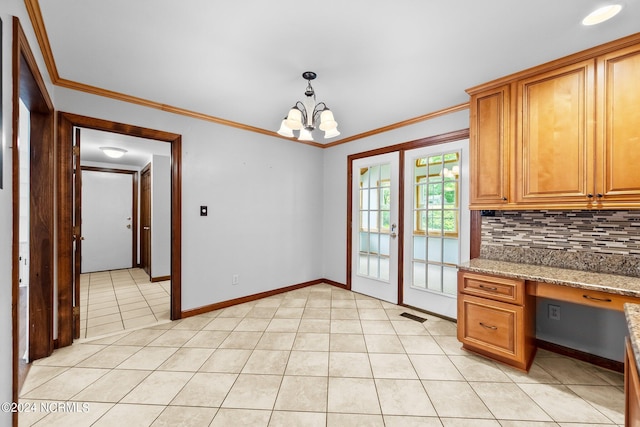 kitchen with decorative backsplash, light stone counters, crown molding, light tile patterned floors, and a notable chandelier