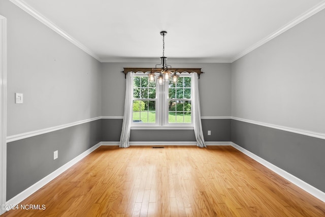 unfurnished room with light hardwood / wood-style flooring, a notable chandelier, and crown molding