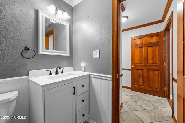 bathroom with tile patterned floors, crown molding, vanity, and toilet