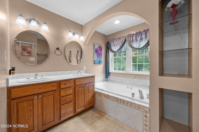 bathroom featuring tile patterned floors, double sink vanity, a textured ceiling, and tiled bath