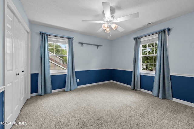 carpeted empty room featuring ceiling fan and a textured ceiling