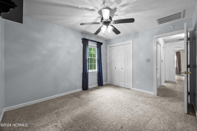 unfurnished bedroom featuring a textured ceiling, a closet, ceiling fan, and carpet