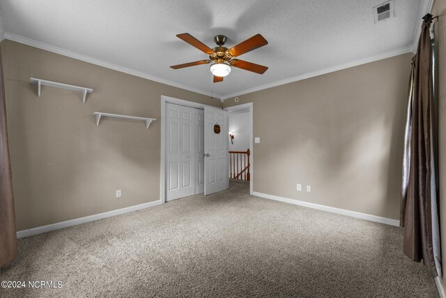 unfurnished bedroom with ceiling fan, carpet flooring, a textured ceiling, and ornamental molding