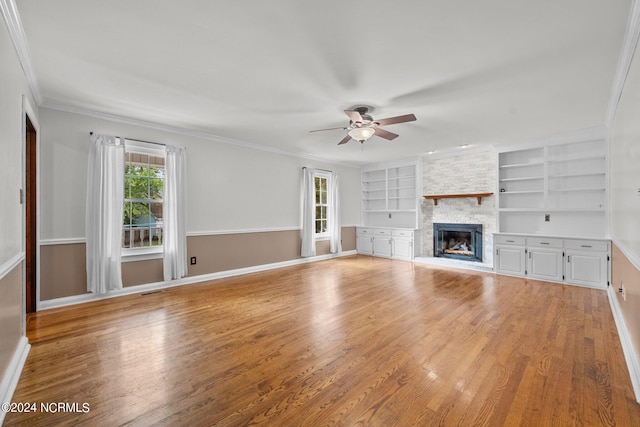 unfurnished living room featuring built in features, a fireplace, light hardwood / wood-style floors, and ceiling fan