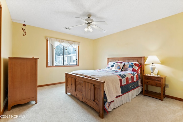 bedroom with a textured ceiling, ceiling fan, and light colored carpet