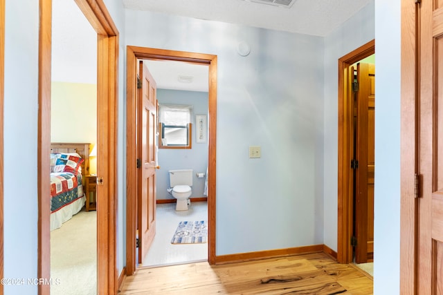 hall with light wood-type flooring and a textured ceiling