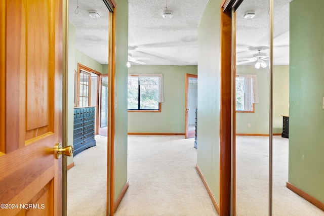 corridor featuring a textured ceiling and light colored carpet