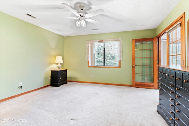 interior space with a textured ceiling, light carpet, and ceiling fan