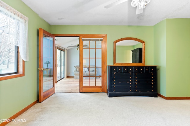 interior space with a closet, ceiling fan, light colored carpet, and french doors