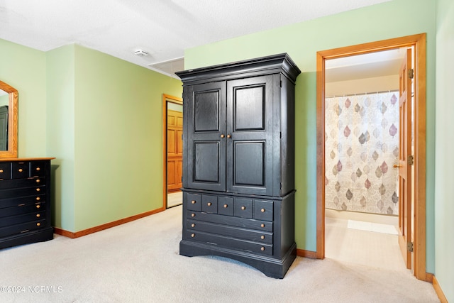 carpeted bedroom featuring ensuite bath and a textured ceiling