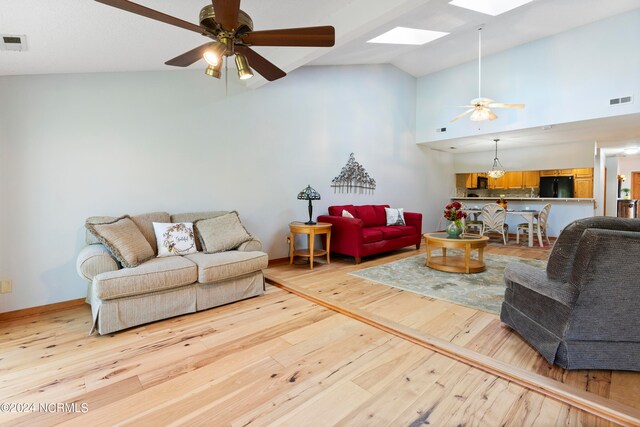 living room featuring ceiling fan, a skylight, and light hardwood / wood-style flooring