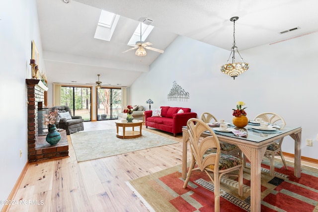 living room with ceiling fan, a skylight, high vaulted ceiling, and hardwood / wood-style flooring