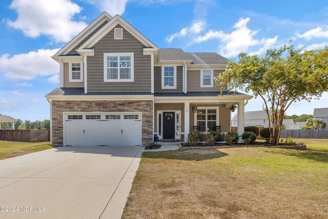 craftsman inspired home featuring covered porch, a garage, and a front lawn