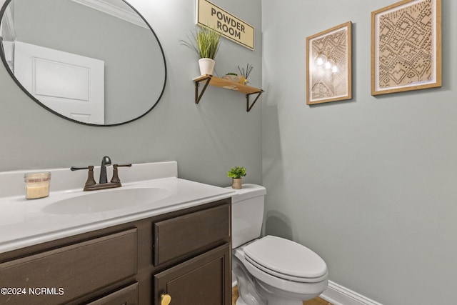 bathroom with toilet, crown molding, and vanity