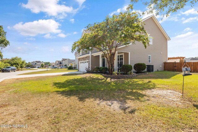 view of front of property with a garage, a front lawn, and central AC unit