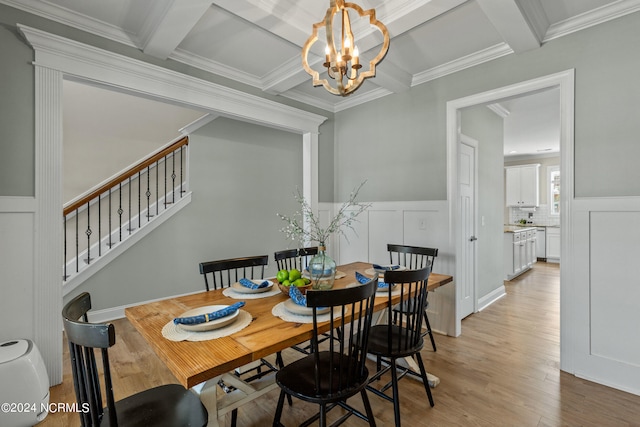 dining space featuring crown molding, coffered ceiling, an inviting chandelier, and light hardwood / wood-style floors