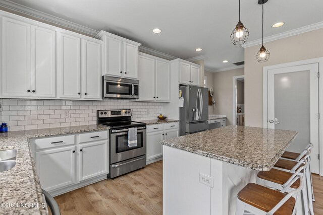 kitchen featuring backsplash, appliances with stainless steel finishes, light hardwood / wood-style floors, a center island, and white cabinets