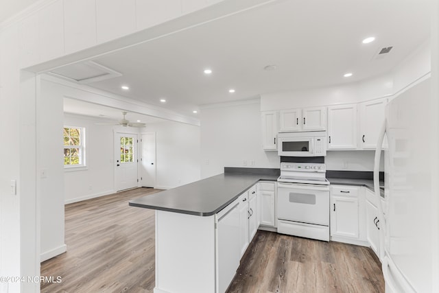 kitchen featuring a peninsula, white appliances, dark countertops, and white cabinets