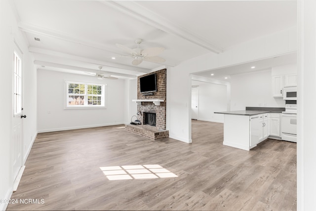 interior space with white appliances, white cabinetry, open floor plan, beam ceiling, and dark countertops