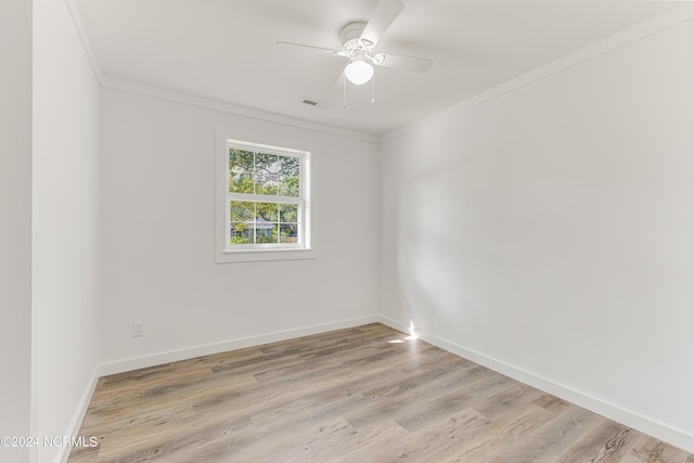 spare room with ceiling fan, visible vents, baseboards, ornamental molding, and light wood finished floors