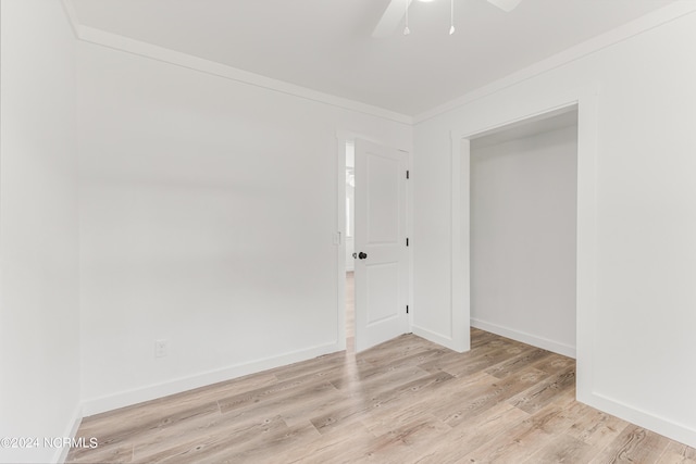 empty room featuring light wood-style floors, baseboards, and crown molding