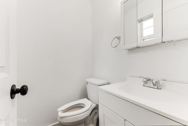 half bath featuring vanity and toilet