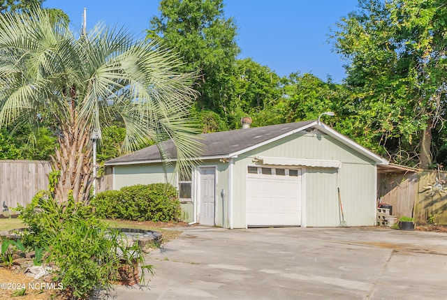 garage featuring fence and concrete driveway