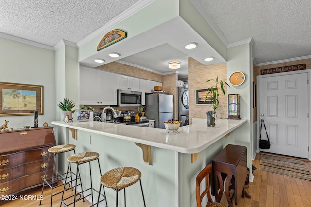 kitchen with appliances with stainless steel finishes, white cabinetry, kitchen peninsula, and a kitchen bar