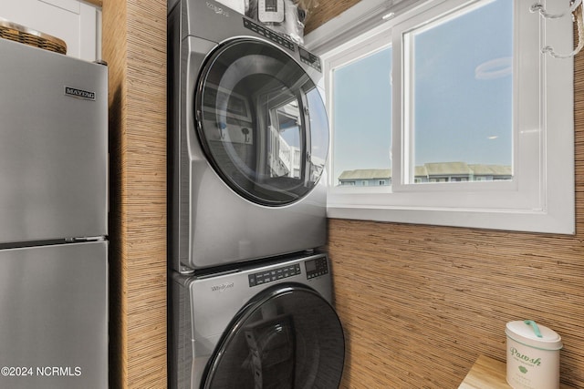 clothes washing area with wood walls and stacked washer / dryer