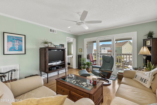 living room with ceiling fan, ornamental molding, light hardwood / wood-style floors, and a textured ceiling