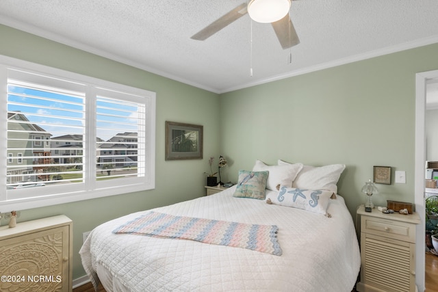 bedroom with a ceiling fan, ornamental molding, and a textured ceiling