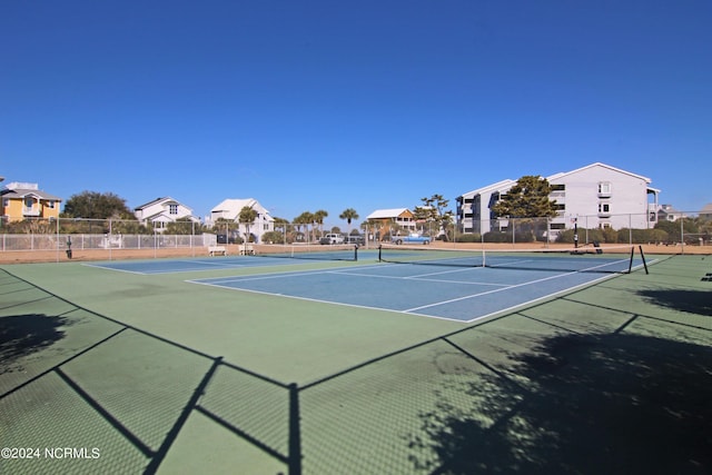 view of tennis court with a residential view and fence